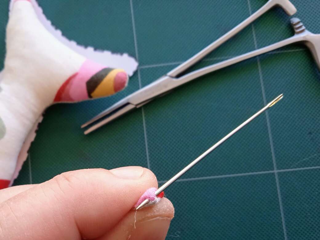 Doll making turning right side out with needle.