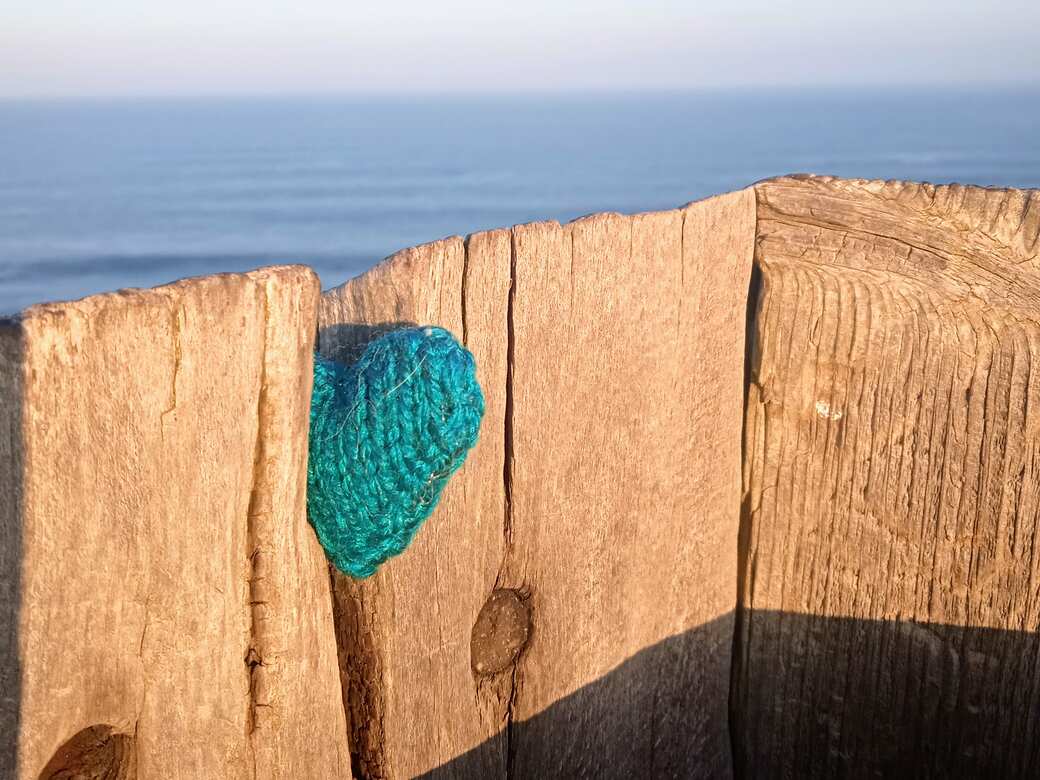 Knitted heart on fence.