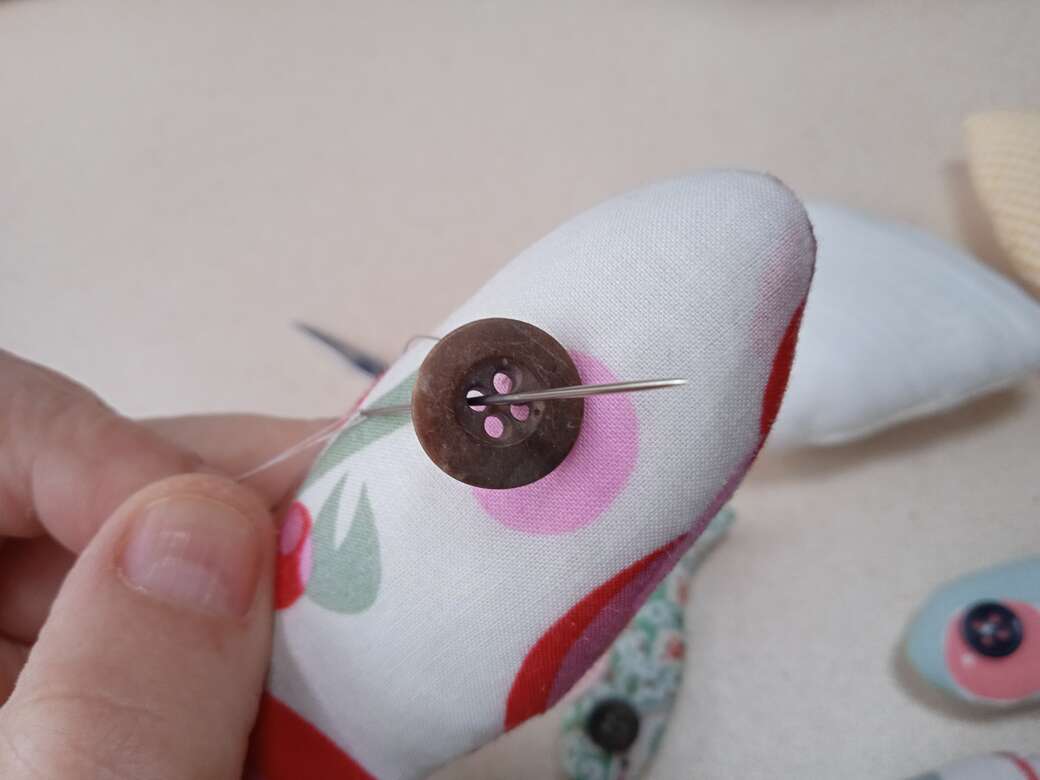 Pass the threaded needle through the hole in the centre of the button.