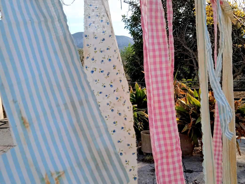 Tea-dyed fabric strips dying outside in the sun.