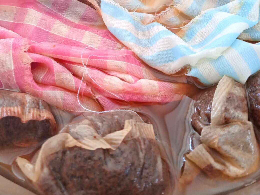 Fabrics fully immersed in tea dyeing bath.